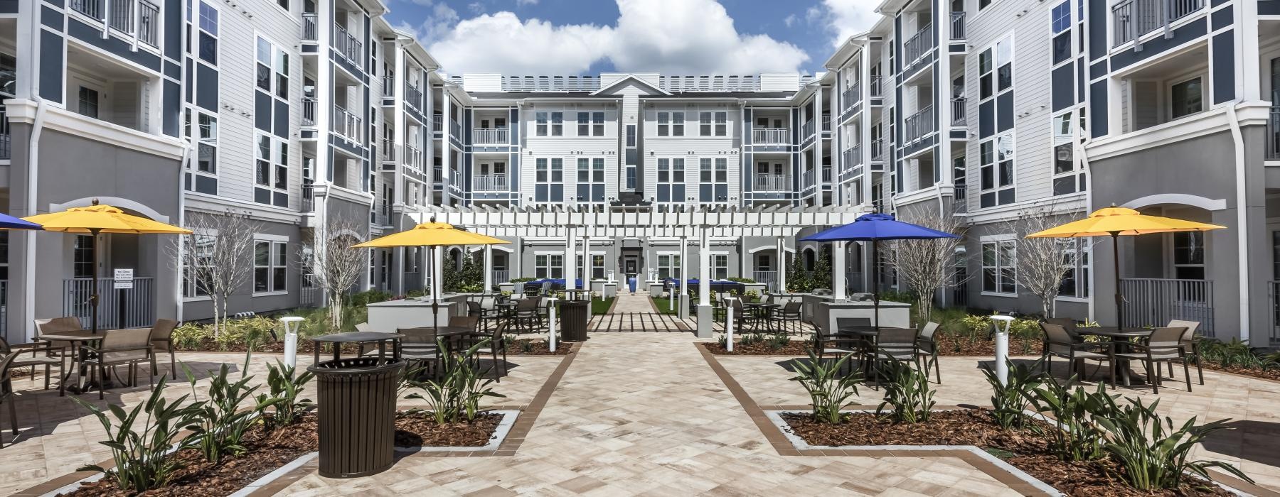 a courtyard with tables and chairs and umbrellas